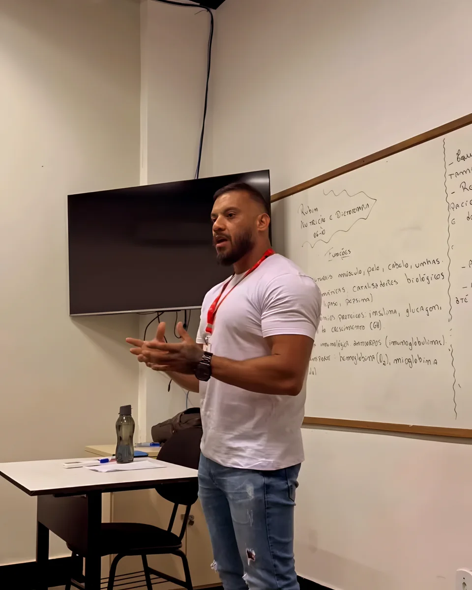 Alexsandro Rubin dando aula em pé, diante do quadro branco, para a turma do curso técnico